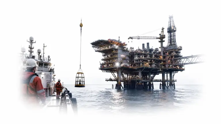 Offshore platform and support vessel in calm sea at dusk, deck lights on